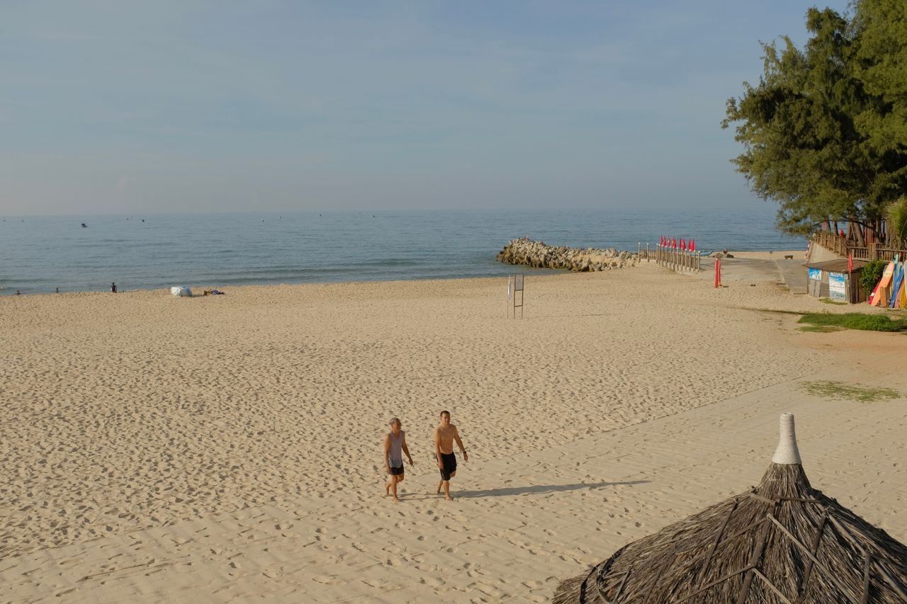 services-img Two people walking along the scenic sandy beach of Binh Thuan, Vietnam on a sunny day.