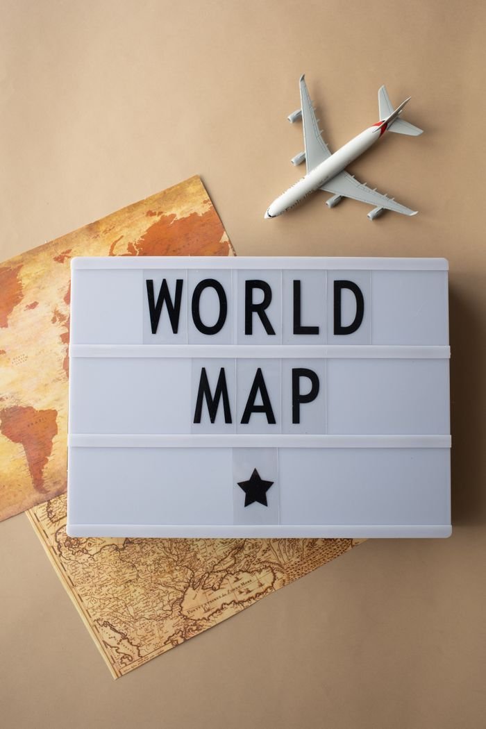 Explore travel concepts with a world map, toy airplane, and lightbox with text.